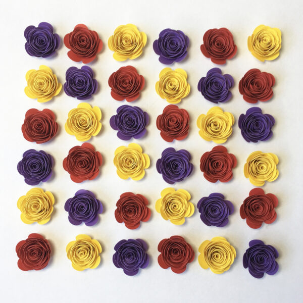 Gerollte Papierblumen in den Farben Flieder, Ziegelrot und Gelb, angeordnet in Diagonalen