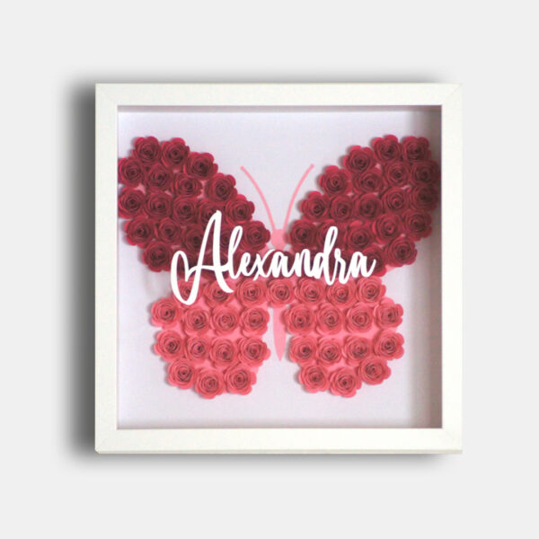 Schmetterling aus gerollten Papierblumen in weißem Bilderrahmen. Darauf der Aufdruck "Alexandra"